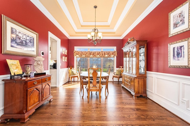 dining area with wainscoting, dark wood-style flooring, a raised ceiling, and a chandelier