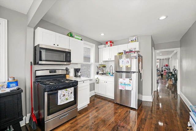 kitchen with tasteful backsplash, light countertops, appliances with stainless steel finishes, dark wood-style floors, and white cabinetry