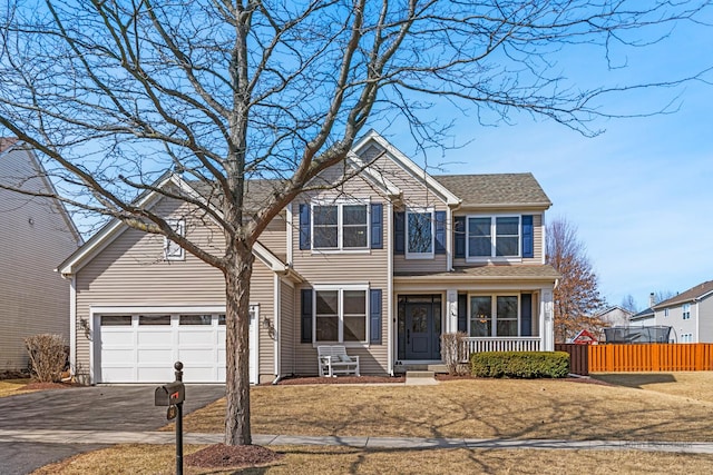 traditional-style home featuring a garage, roof with shingles, driveway, and fence