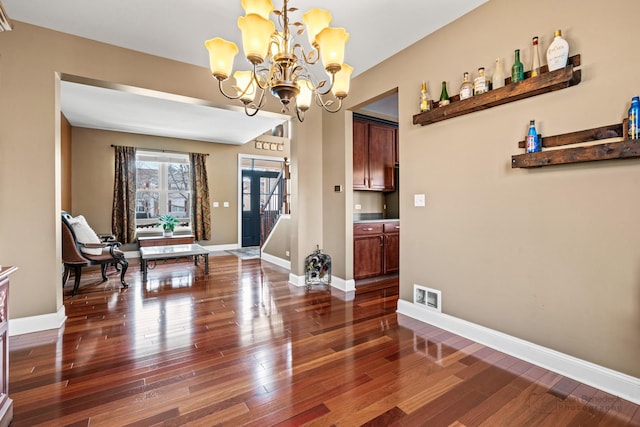 dining room featuring dark wood finished floors, visible vents, an inviting chandelier, and baseboards