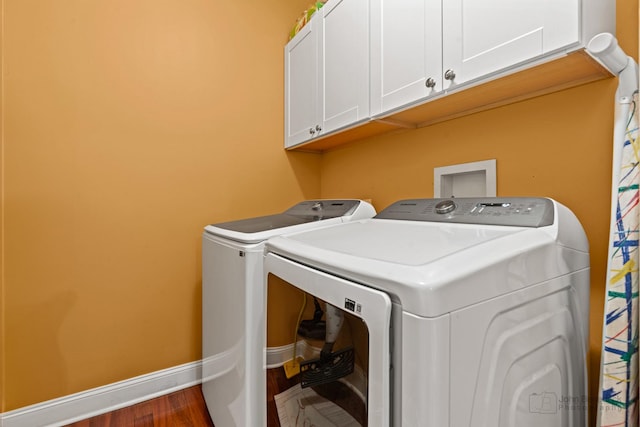 washroom featuring separate washer and dryer, wood finished floors, cabinet space, and baseboards