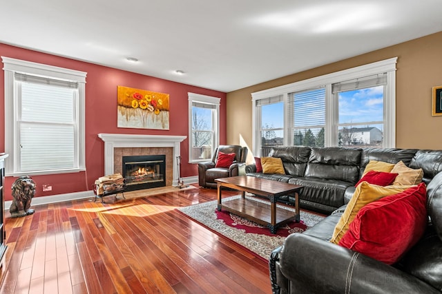 living area featuring baseboards, hardwood / wood-style floors, and a tile fireplace