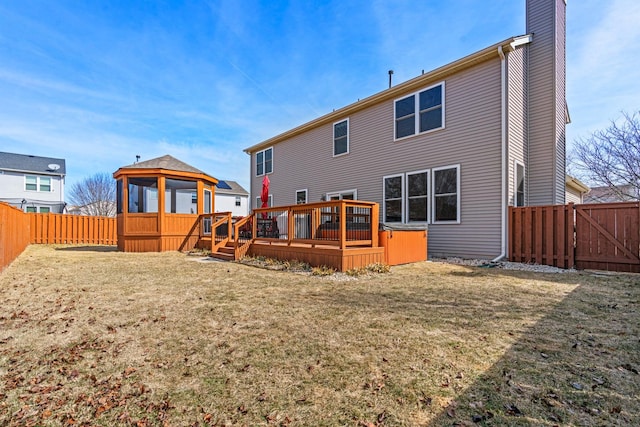 rear view of house featuring a yard, a wooden deck, a fenced backyard, and a chimney