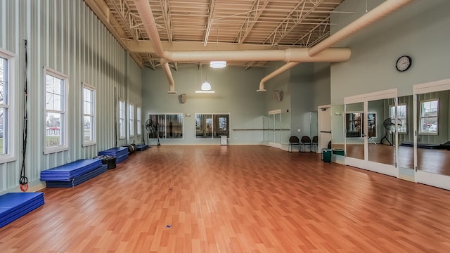 exercise room featuring a towering ceiling and wood finished floors