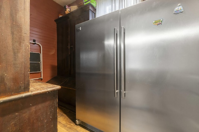 kitchen with high end fridge, wood walls, and light wood finished floors