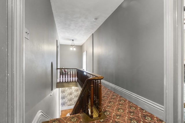 hall featuring an upstairs landing and baseboards
