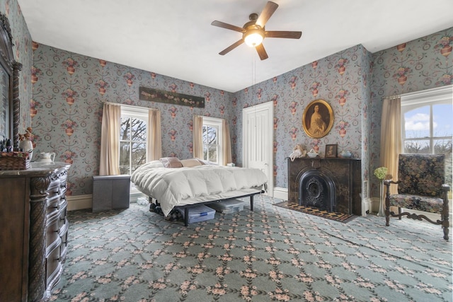 bedroom with wallpapered walls, a ceiling fan, baseboards, and carpet floors