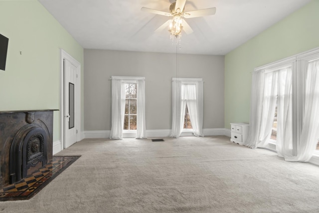 carpeted living room with a fireplace with flush hearth, visible vents, baseboards, and ceiling fan