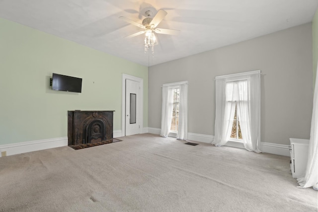 unfurnished living room with visible vents, a fireplace with flush hearth, a ceiling fan, carpet, and baseboards