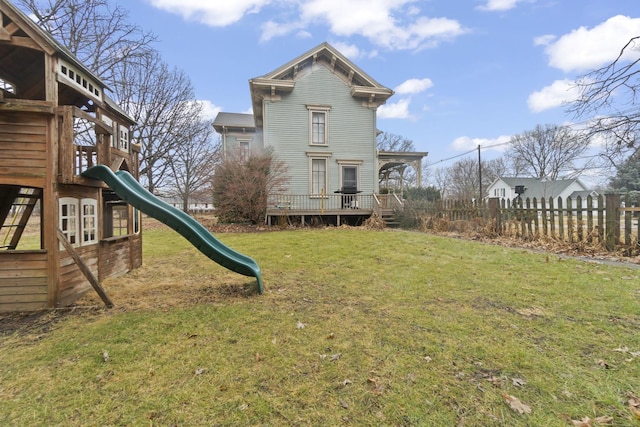 exterior space featuring a deck, fence, and a lawn