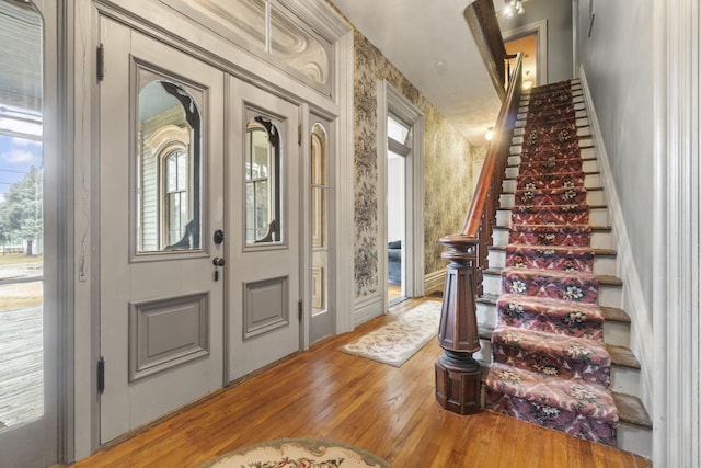 foyer featuring stairway, hardwood / wood-style floors, and wallpapered walls