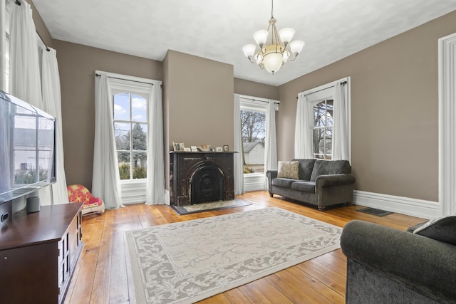 living room featuring visible vents, baseboards, a fireplace, hardwood / wood-style flooring, and a notable chandelier