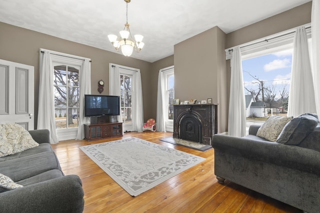living area with a notable chandelier, a fireplace, and hardwood / wood-style flooring