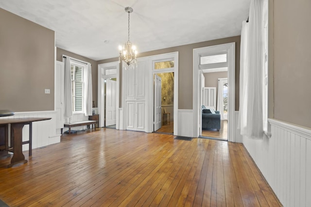 interior space featuring an inviting chandelier, hardwood / wood-style flooring, and a wainscoted wall