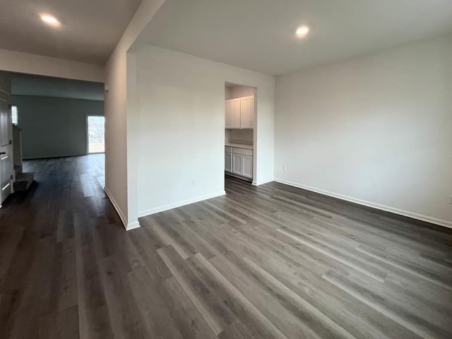 spare room featuring baseboards and dark wood finished floors