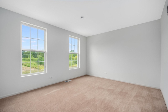 spare room featuring visible vents, light colored carpet, and baseboards