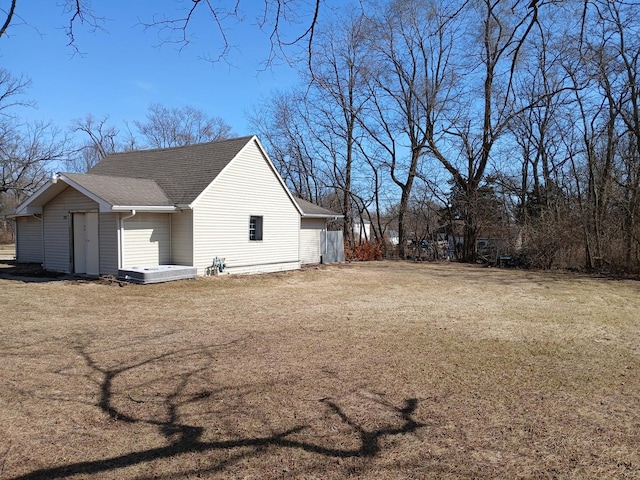 view of side of property featuring a lawn and roof with shingles