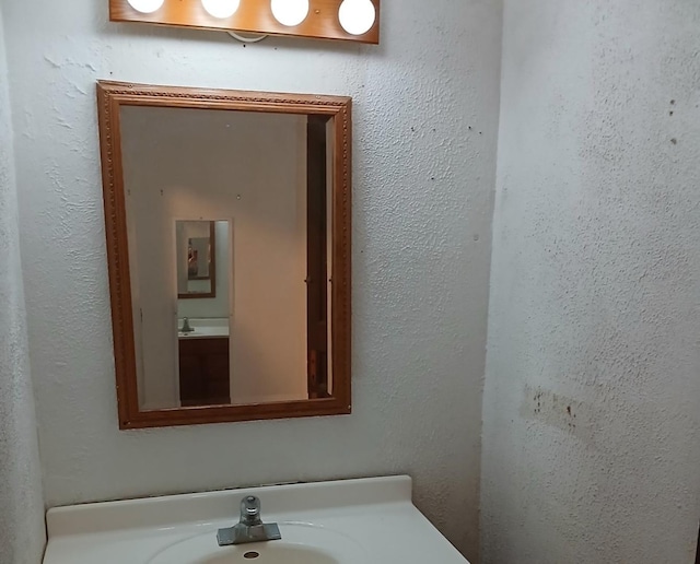 bathroom featuring a textured wall and a sink