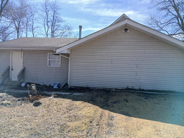 view of side of property featuring roof with shingles and entry steps