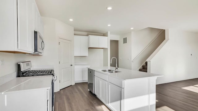 kitchen with dark wood finished floors, white cabinets, appliances with stainless steel finishes, and a sink