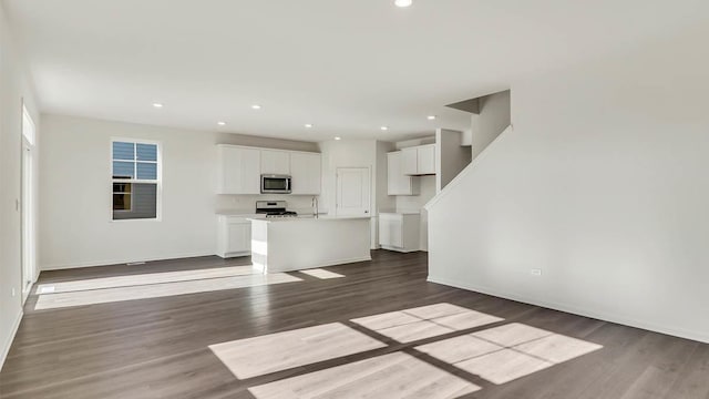 unfurnished living room with dark wood-style floors, recessed lighting, baseboards, and a sink