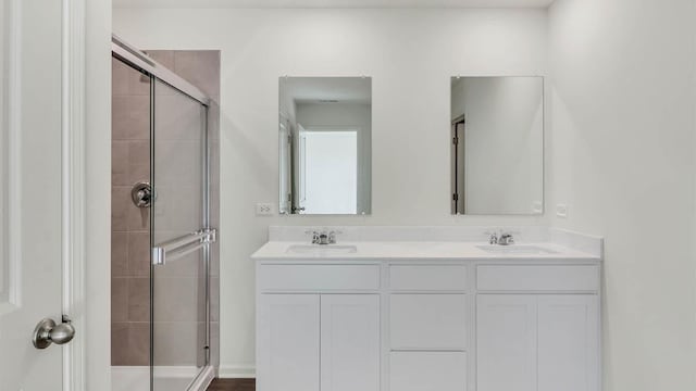 bathroom with a sink, a stall shower, and double vanity