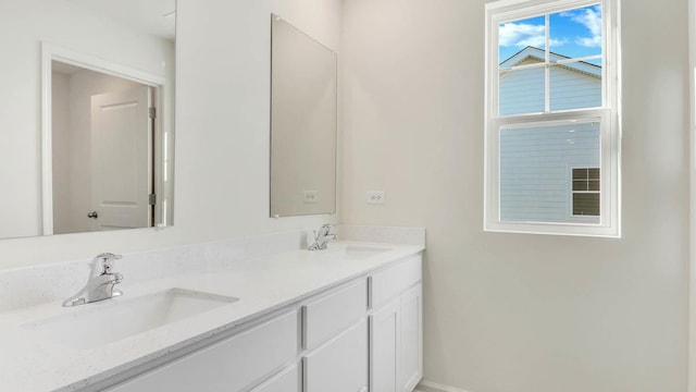 full bath with a sink, baseboards, and double vanity