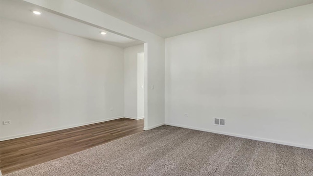 empty room featuring dark colored carpet, visible vents, baseboards, and recessed lighting