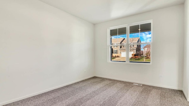 carpeted spare room featuring visible vents and baseboards