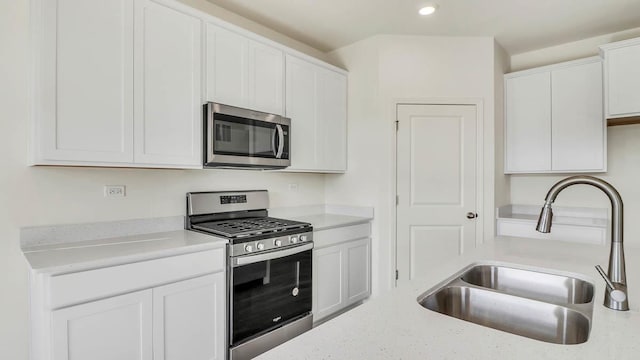 kitchen featuring recessed lighting, appliances with stainless steel finishes, white cabinetry, and a sink