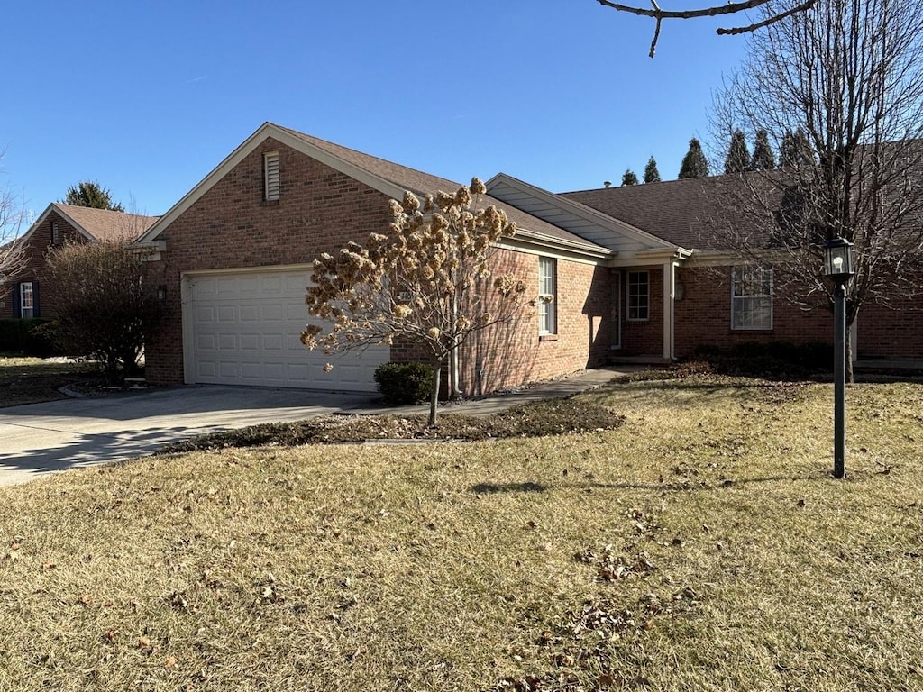 view of front of home featuring concrete driveway, a garage, brick siding, and a front yard