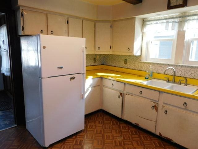 kitchen with light countertops, freestanding refrigerator, and a sink