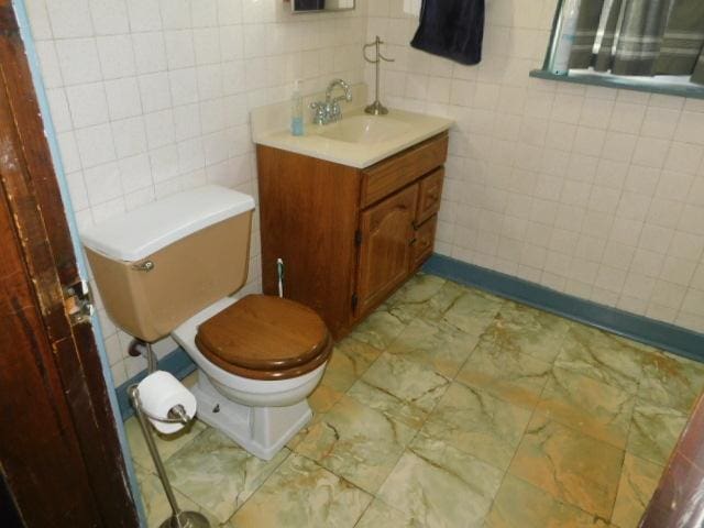 half bathroom with toilet, tile walls, and vanity