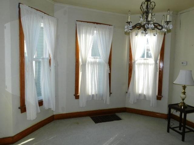 interior space featuring a chandelier, visible vents, baseboards, and carpet