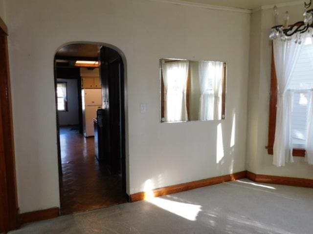 spare room featuring baseboards and arched walkways