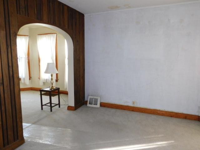 spare room featuring arched walkways, visible vents, and baseboards