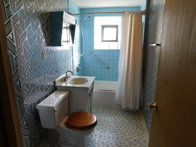 bathroom featuring tile walls, vanity, toilet, and shower / tub combo with curtain