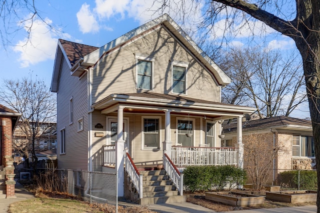 view of front of house with covered porch, fence, and a garden