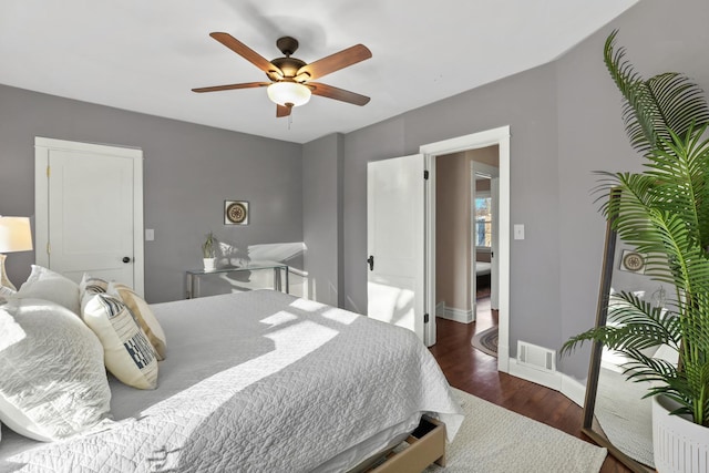 bedroom featuring ceiling fan, visible vents, baseboards, and wood finished floors