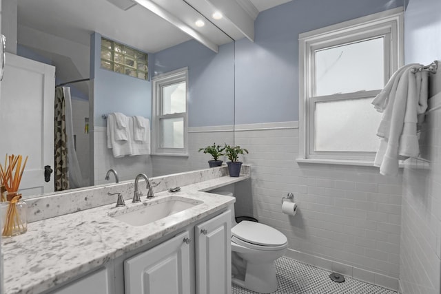 full bathroom with tile patterned floors, toilet, tile walls, wainscoting, and vanity