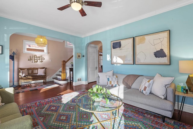 living room with a ceiling fan, wood finished floors, arched walkways, baseboards, and stairs