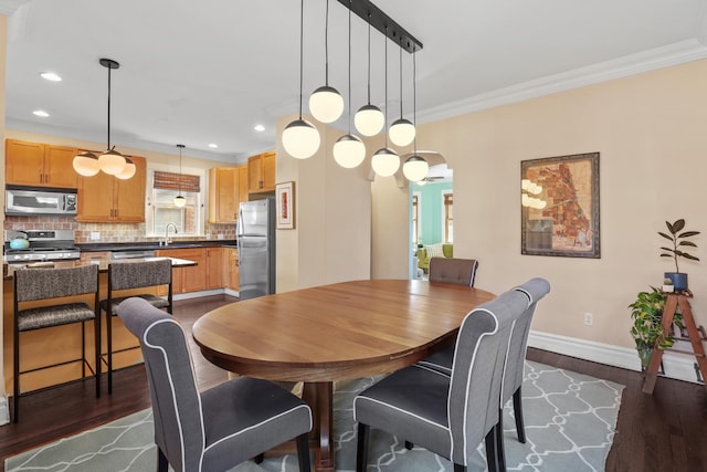 dining area featuring dark wood-style floors, recessed lighting, arched walkways, crown molding, and baseboards