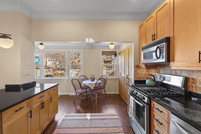 kitchen featuring tasteful backsplash, crown molding, dark stone countertops, appliances with stainless steel finishes, and dark wood-style flooring