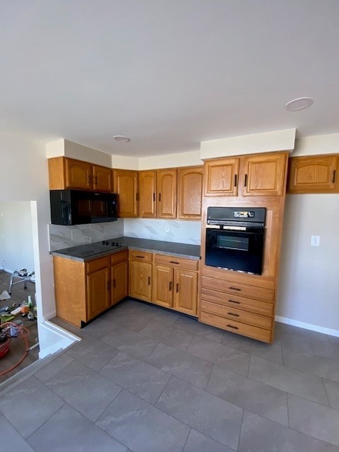 kitchen featuring black appliances, baseboards, and brown cabinets