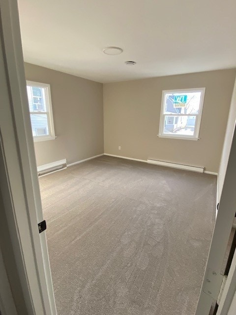 carpeted empty room with a wealth of natural light, a baseboard radiator, and baseboards