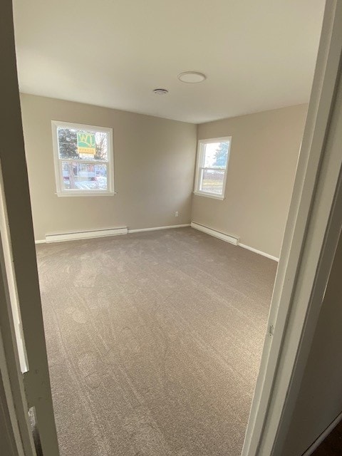 unfurnished room with a baseboard heating unit, baseboards, dark carpet, and a baseboard radiator