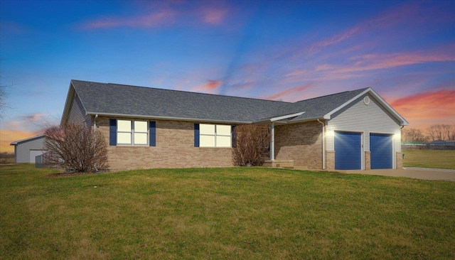 single story home featuring brick siding, a lawn, driveway, and an attached garage