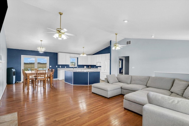 living room with hardwood / wood-style flooring, ceiling fan with notable chandelier, and visible vents