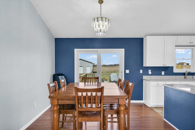 dining space with baseboards, a chandelier, and dark wood finished floors