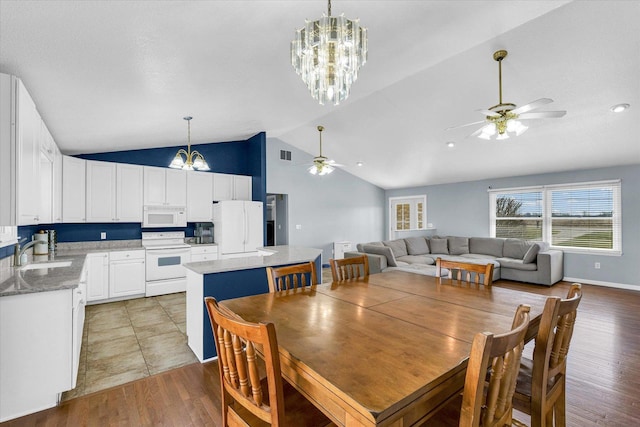 dining room with lofted ceiling, baseboards, ceiling fan with notable chandelier, visible vents, and light wood-style floors